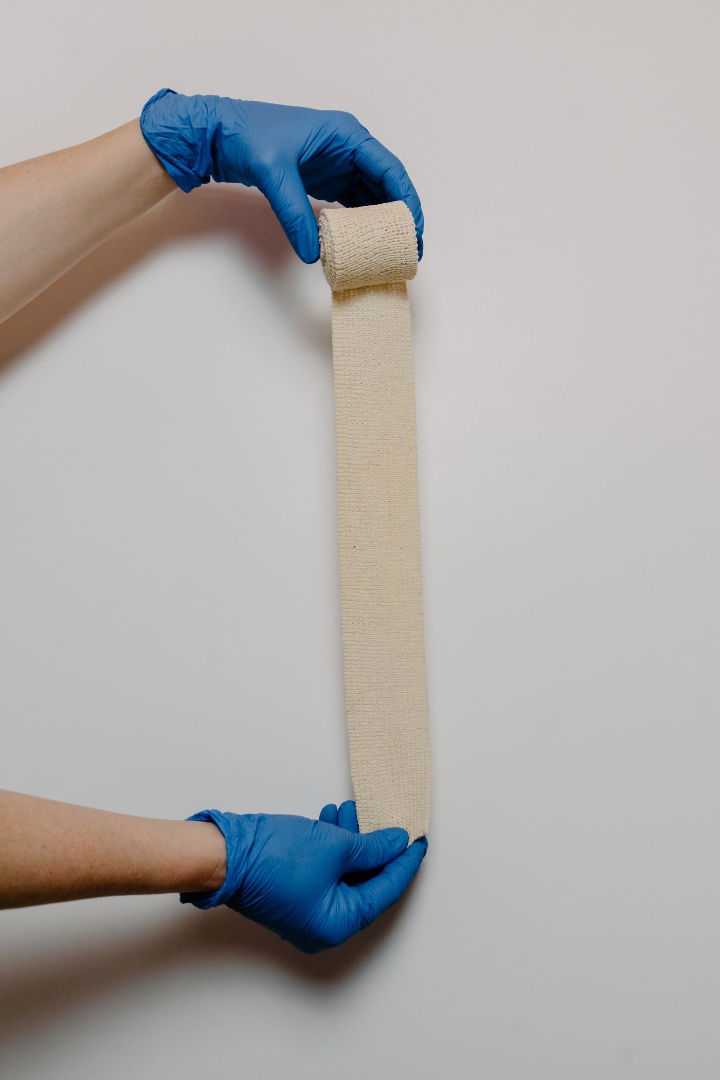 Gloved hands holding gauze bandages, illustrating first-aid supplies